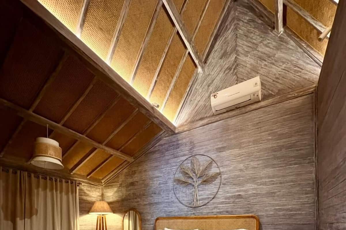 A bedroom with a wooden bed, a circular wall decoration, a bedside table, and a hanging light fixture.
