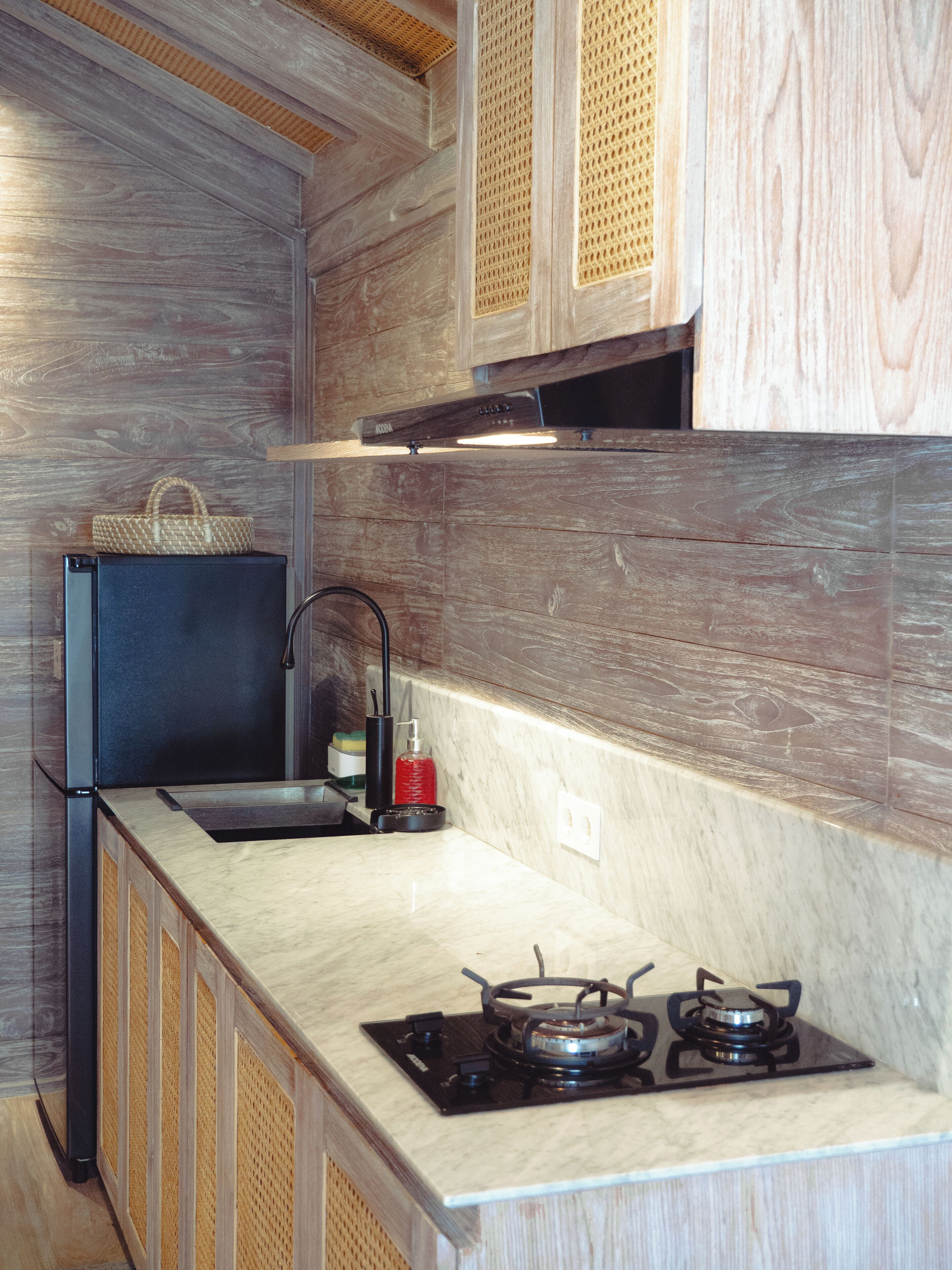 Una cocina con estufa integrada, refrigerador y armarios de madera.