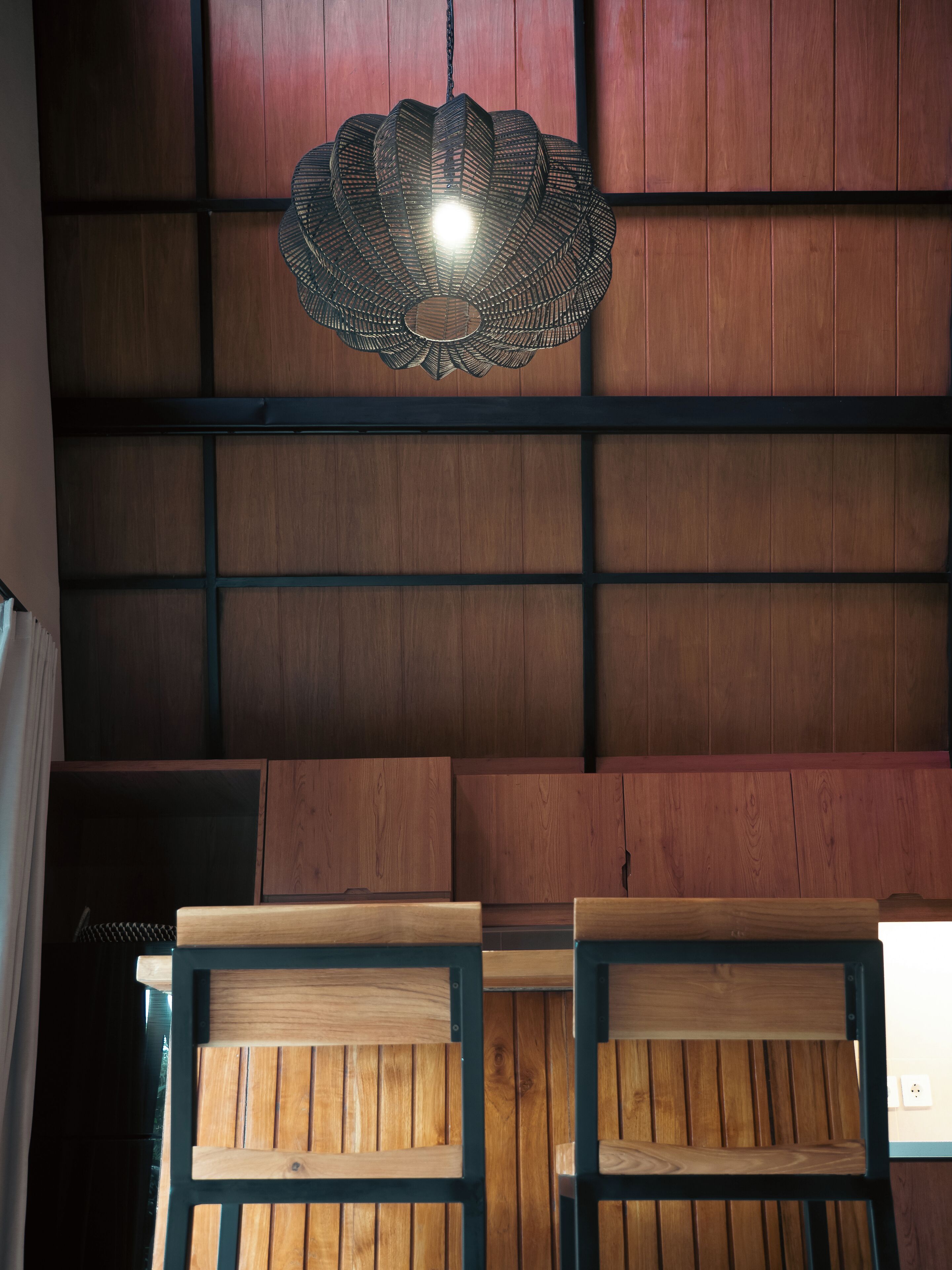 A room with wooden panel walls, a hanging light fixture, and two wooden chairs.