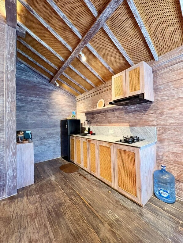 A modern kitchen with wooden cabinetry, a gas stove, and a built-in refrigerator. - TWINSEAS VILLA (Ungasan)