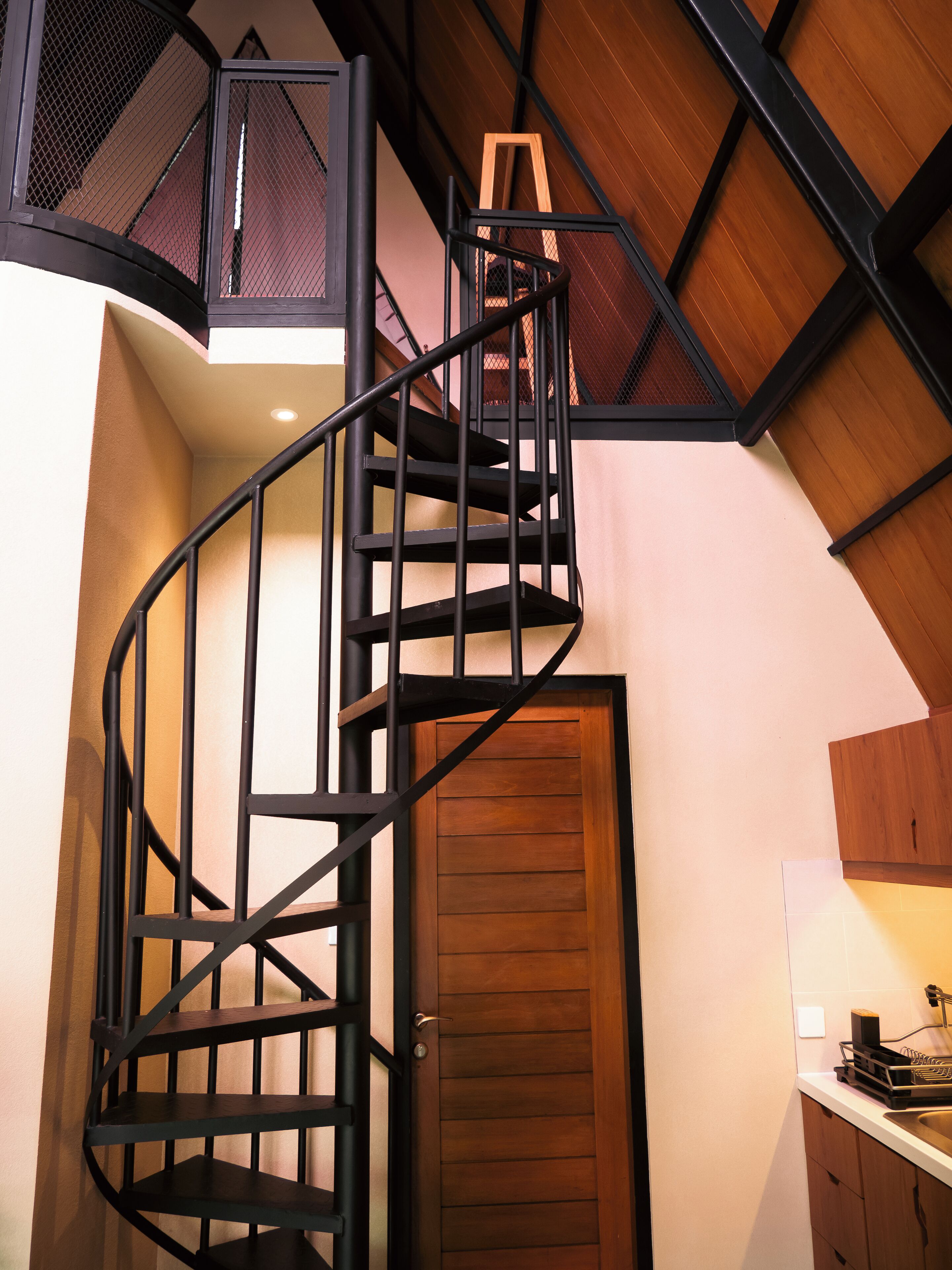 A spiral staircase with a wooden door at the bottom.