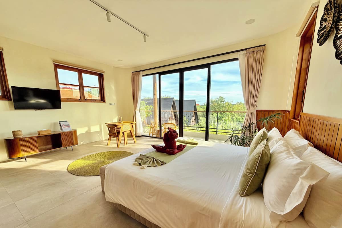 A modern bedroom with a large bed, a TV, a desk, and a balcony with a view.