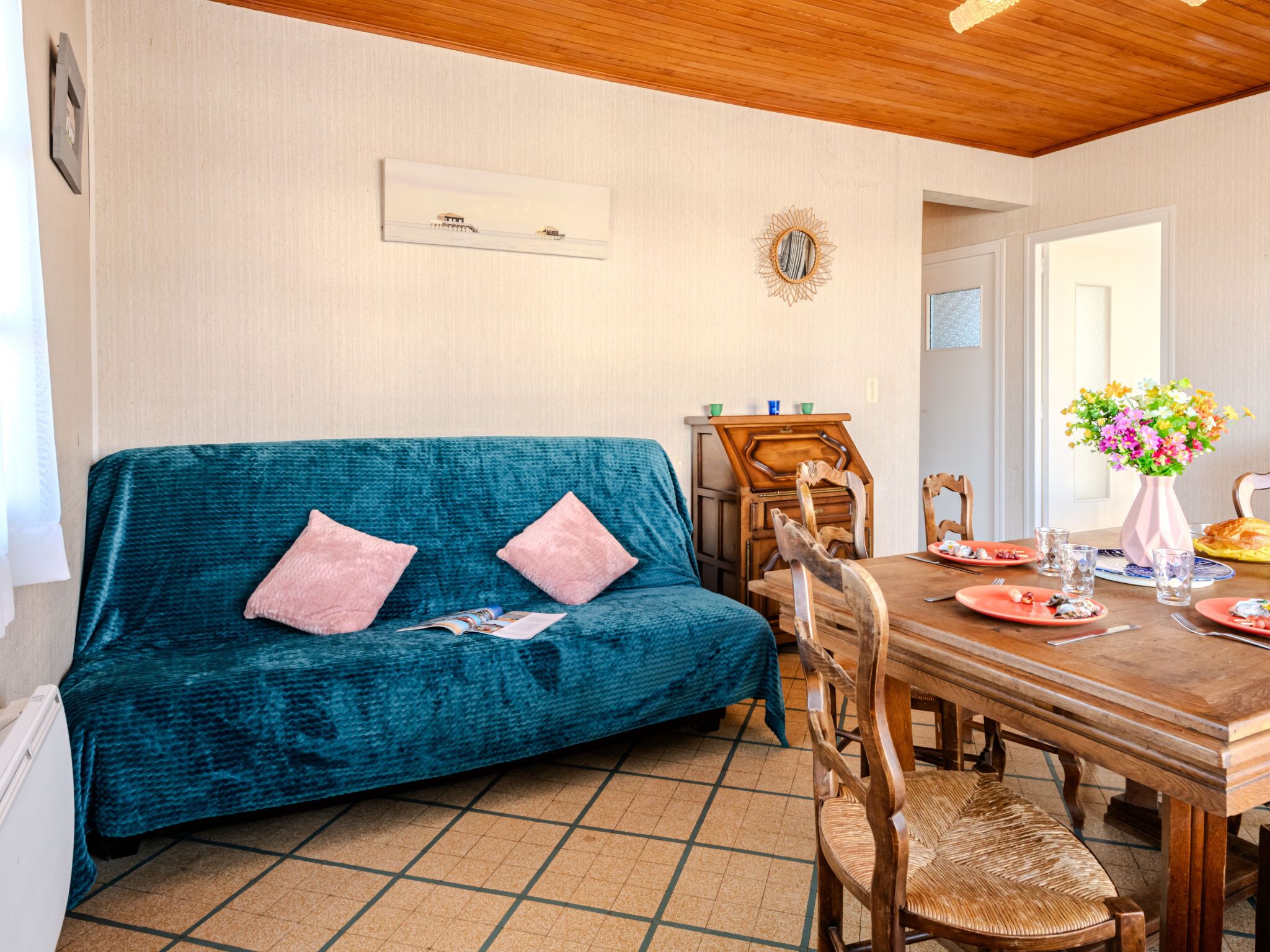 Un salon chaleureux avec un canapé de couleur turquoise, une table à manger en bois et des chaises.