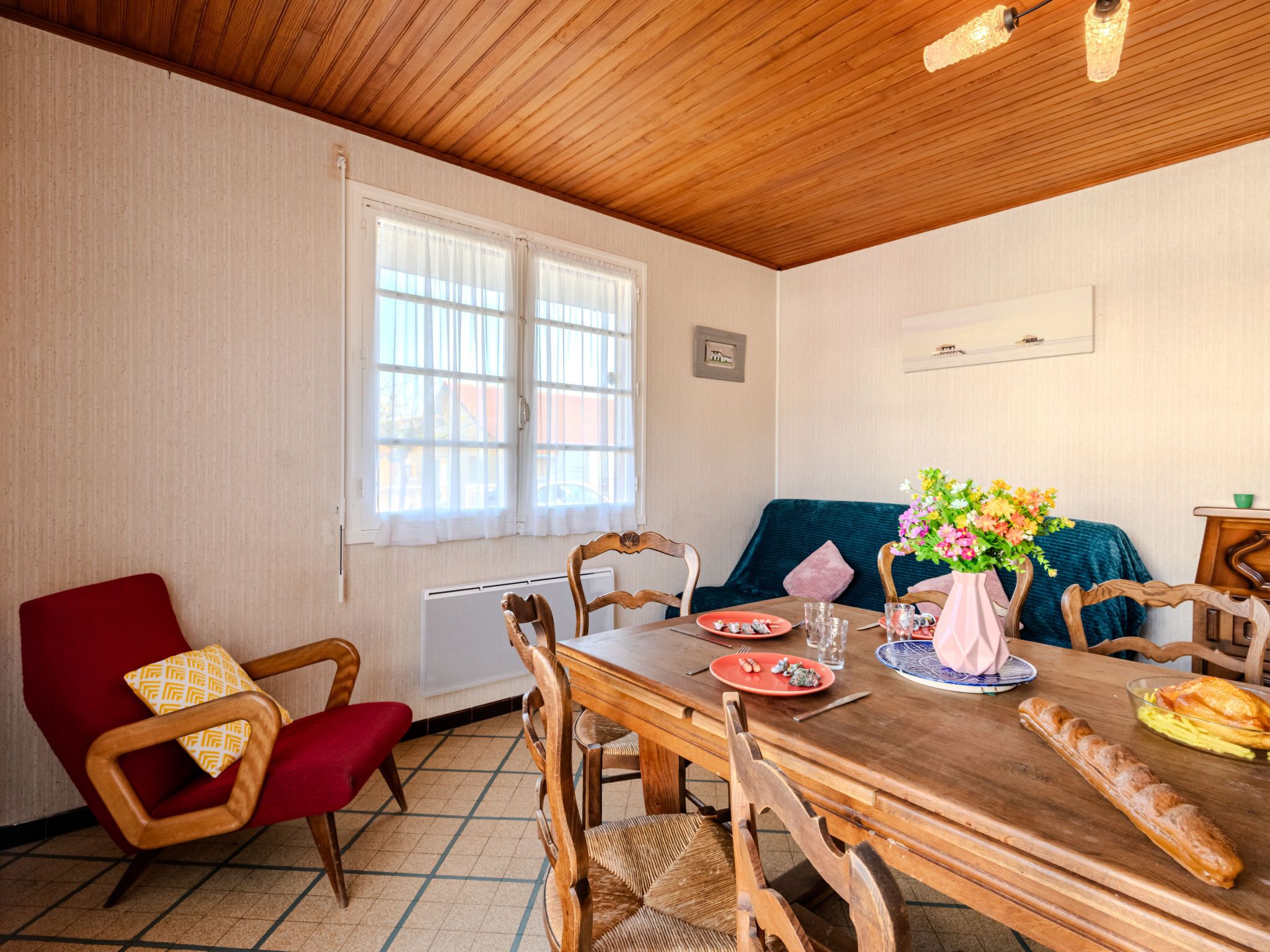 A dining area with a wooden table, chairs, and a window with curtains.