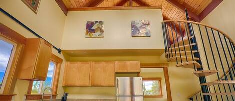 A kitchen with wooden cabinets, a stainless steel refrigerator, and a wooden countertop.