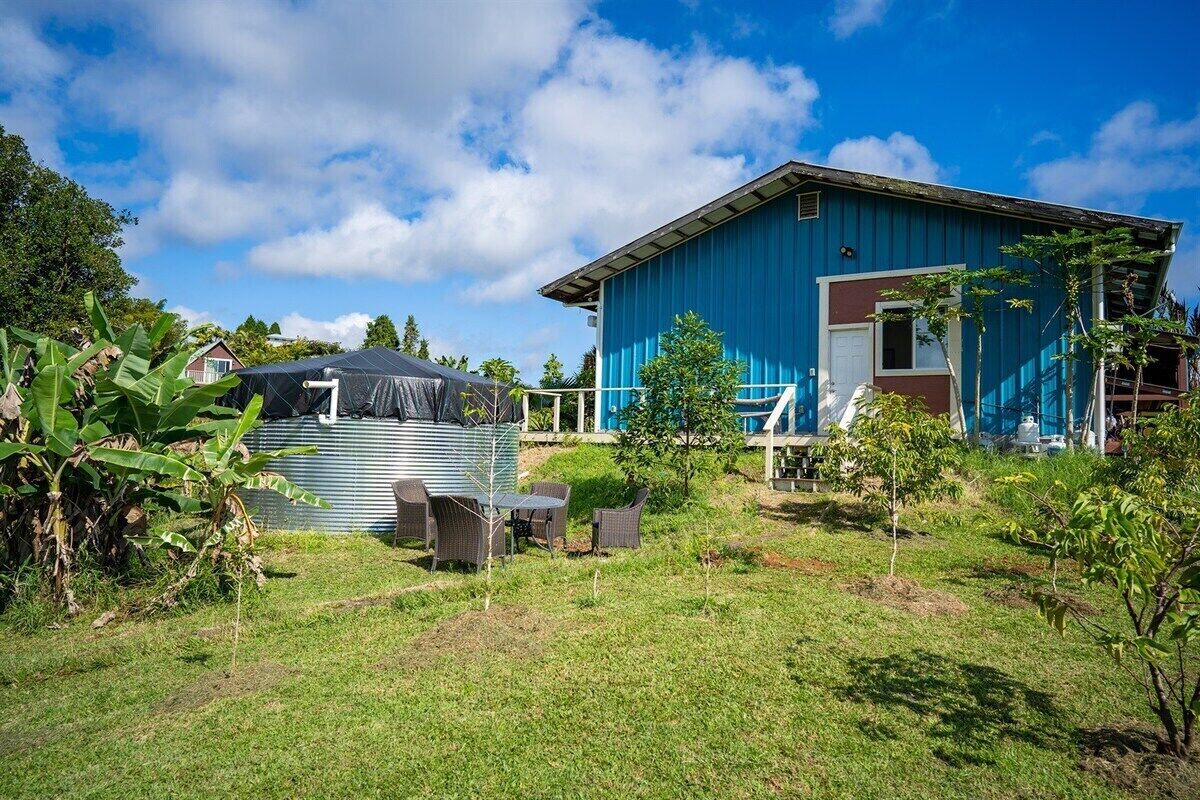 A blue house with a covered outdoor area and a small garden.