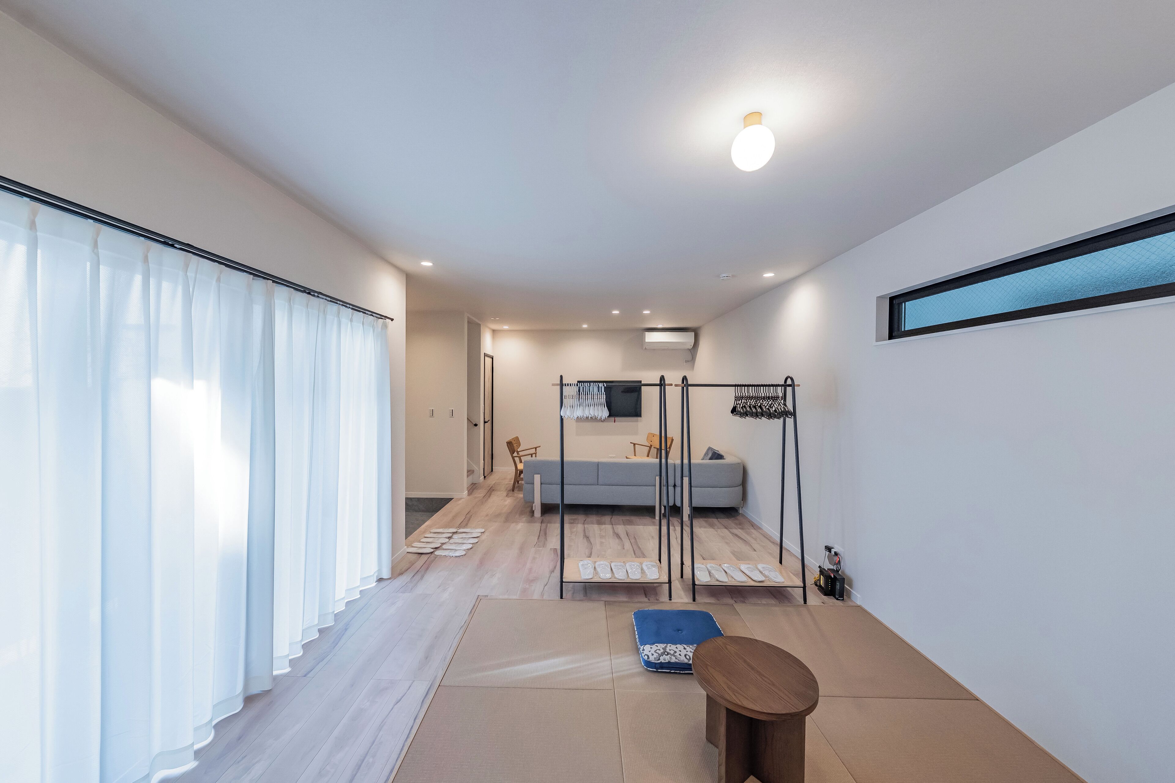 A modern, minimalist room with a sofa, a small table, and a TV mounted on the wall.