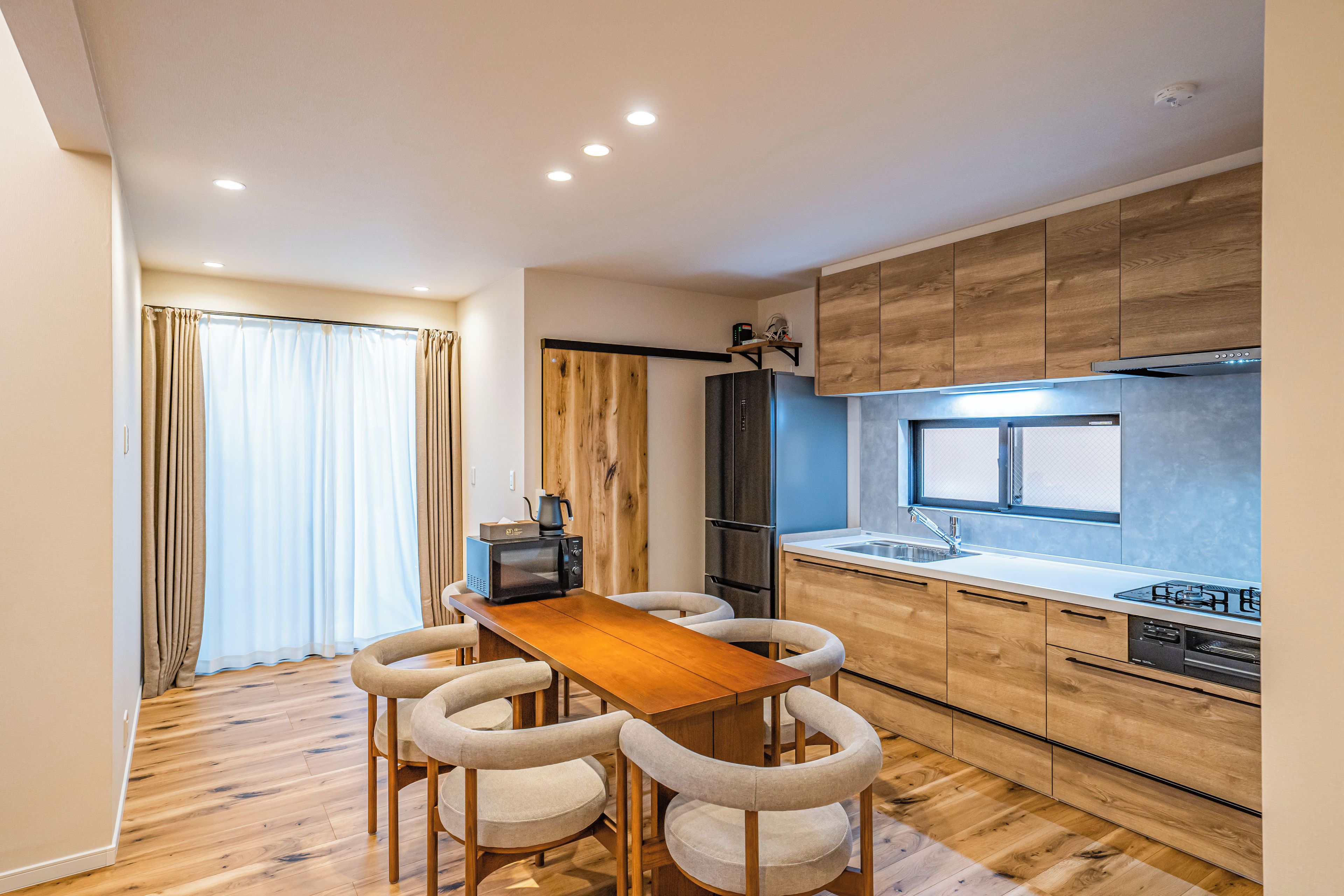 Eine moderne Küche mit Holzschränken, einem Einbauofen und einem Essbereich mit Holztisch und Stühlen.