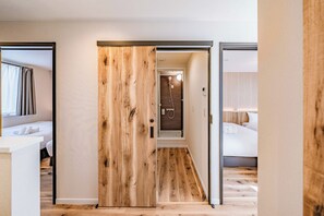 Une chambre d’hôtel avec un plancher en bois, un lit avec du linge de lit blanc et une salle de bain avec douche.