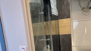 Une salle de bain moderne avec une douche à parois de verre, des toilettes et un porte-serviettes.