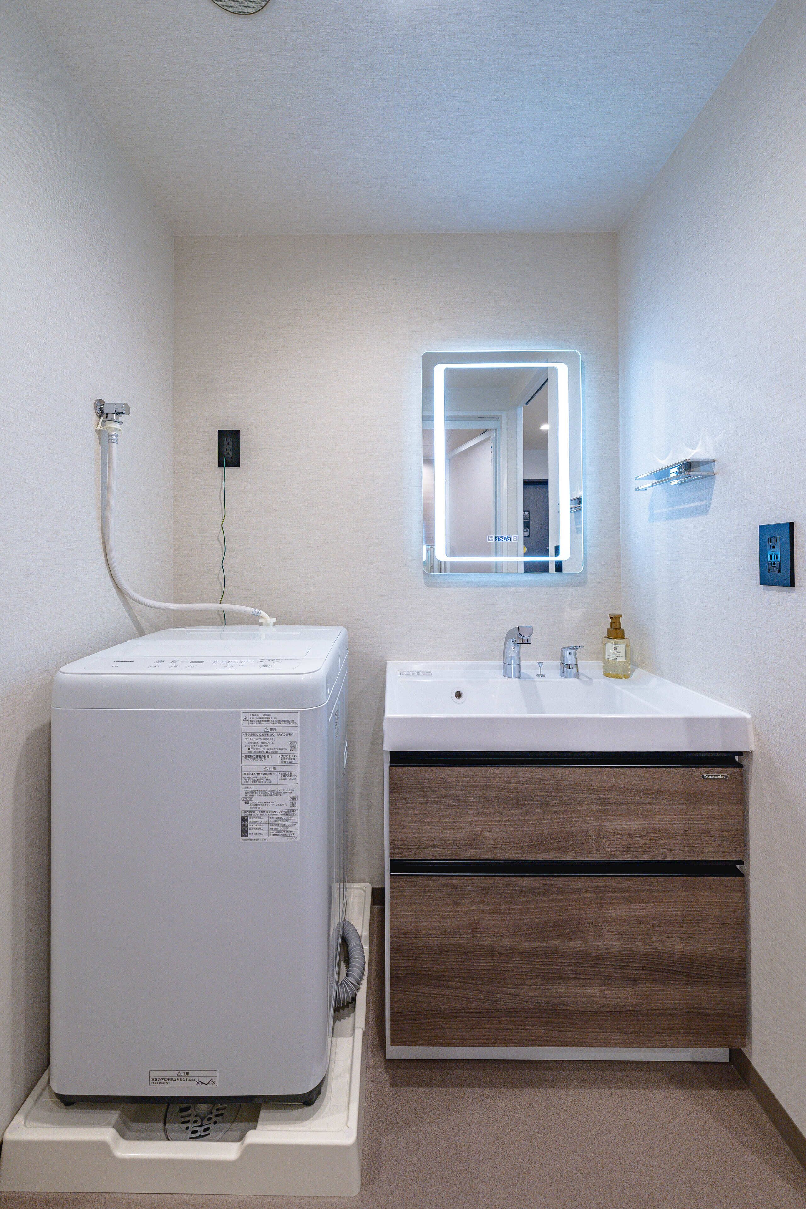 Une salle de bain avec un lavabo blanc, un miroir et un chauffe-eau blanc.