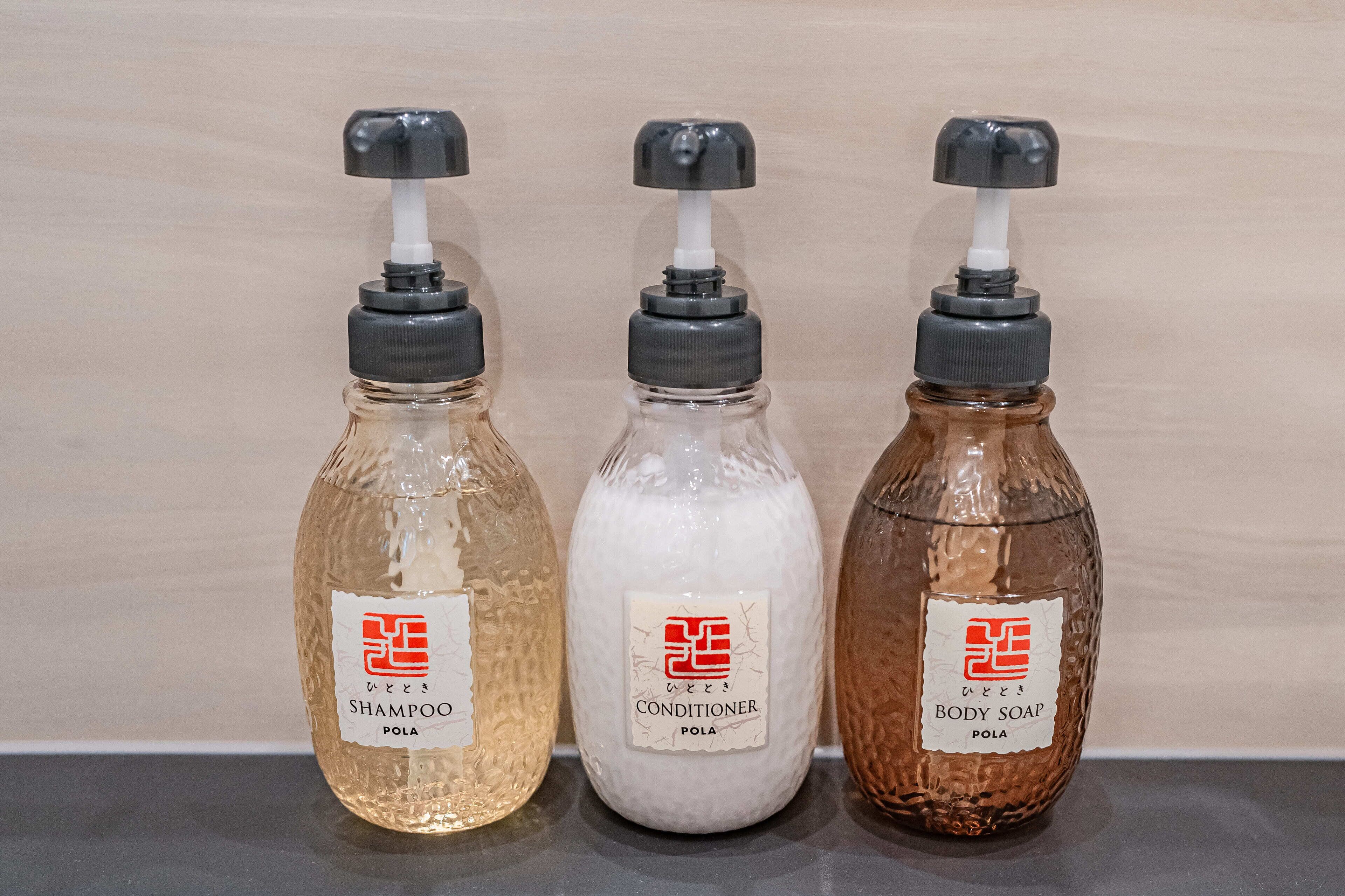 Three bottles of liquid soap with pumps, labeled as shampoo, conditioner, and body soap.