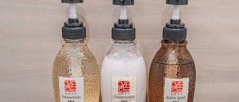 Three bottles of liquid soap with pumps, labeled as shampoo, conditioner, and body soap.
