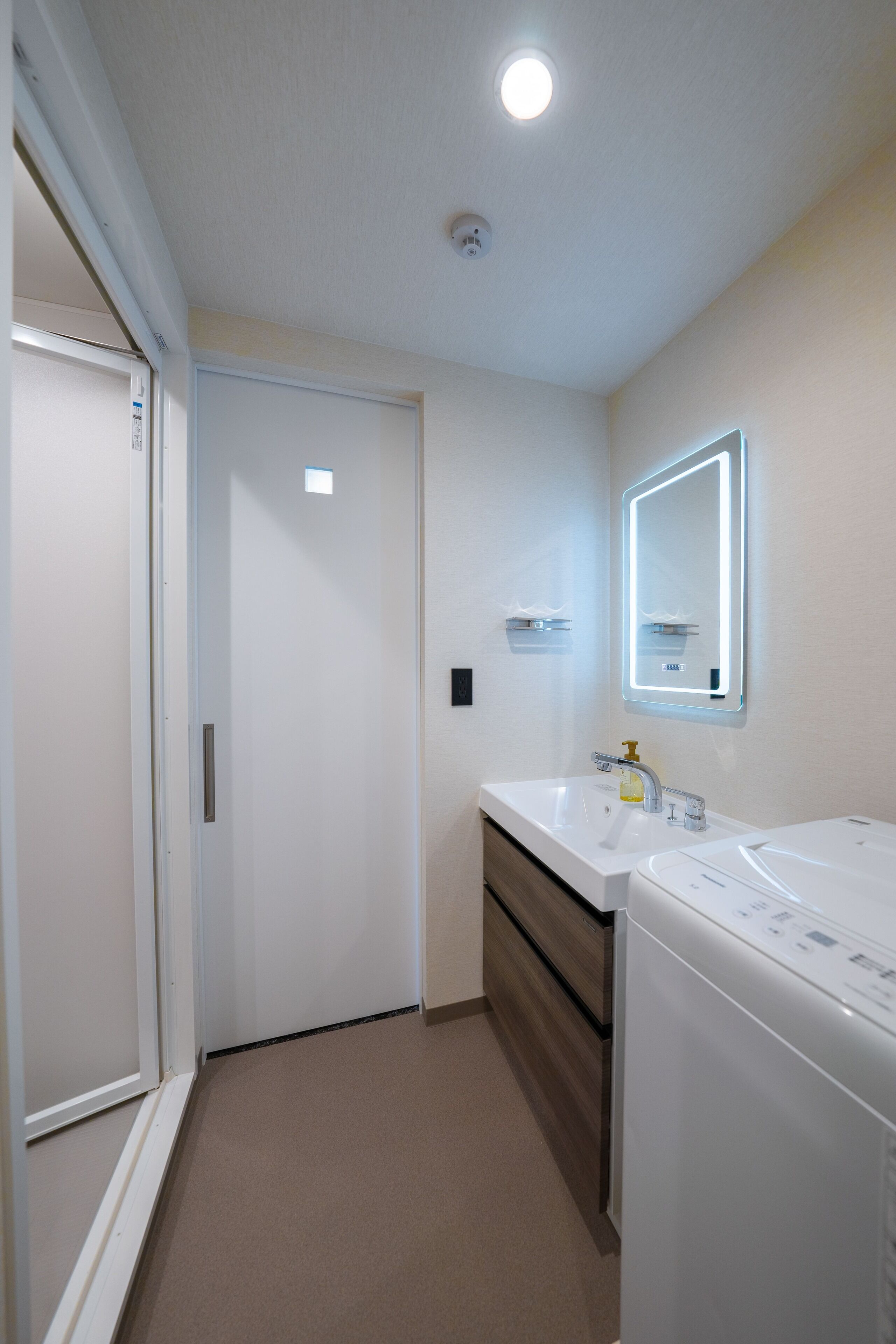 Een moderne badkamer met twee wasbakken, een spiegel en een wasmachine.