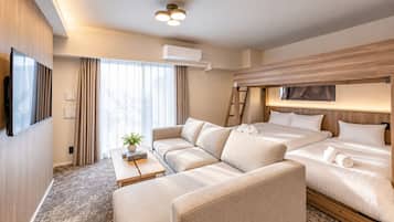A hotel room with a sofa, a bed, a TV, and an air conditioning unit.