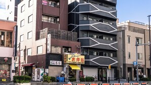 Un edificio moderno con varios pisos, una combinación de espacios comerciales y residenciales, y un cielo despejado.