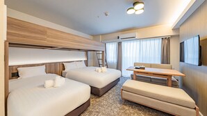 Habitación de hotel con dos camas, un escritorio, un sofá y una televisión.