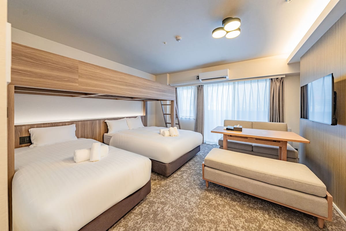 Une chambre d’hôtel avec deux lits, un bureau, un canapé et une télévision.