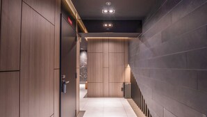 Un pasillo moderno con paneles de madera, piso de baldosas e iluminación empotrada.