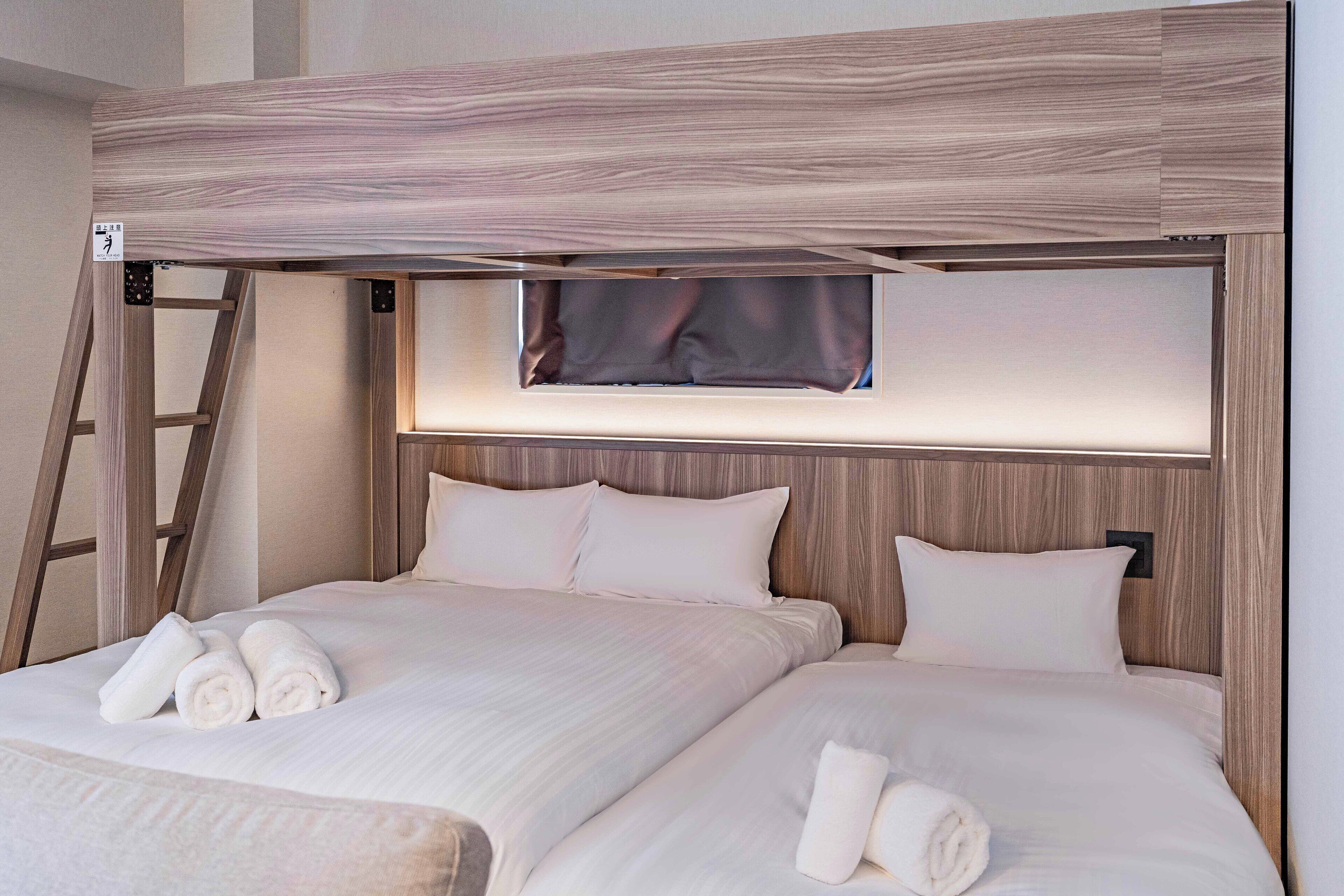 Una cama doble con cabecera de madera, dos almohadas y dos toallas enrolladas.