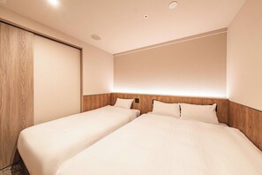 Habitación de hotel con dos camas individuales, un armario de madera y un ventanal grande.