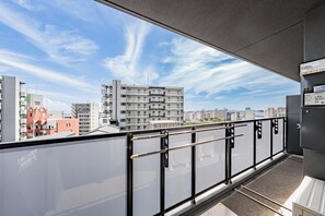 Un balcón con vista a la ciudad, barandas de metal y una estructura metálica negra.