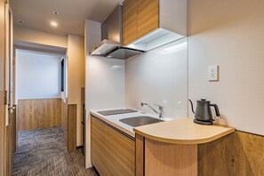 A modern kitchen with a built-in oven, a sink, and a kettle on the countertop.