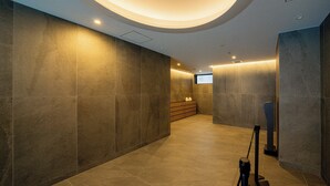 A modern hallway with a curved ceiling, recessed lighting, and a bench with a small table. - Apartment Hotel 11 Namba Minami IV (Osaka)