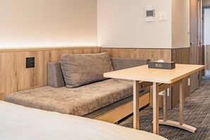 Habitación de hotel con sofá, una mesita y una mesita de noche con un box de pañuelos.