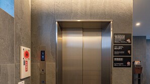 An elevator with a digital display, emergency buttons, and a sign with instructions. - Apartment Hotel 11 Namba Minami IV (Osaka)