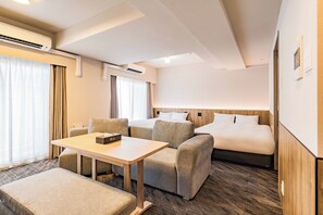 Une chambre d’hôtel avec un lit, deux canapés, une petite table et une fenêtre avec des rideaux.