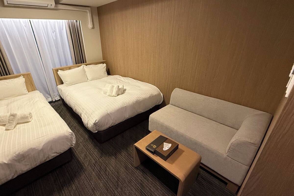 Ein Hotelzimmer mit zwei Betten, einem Schlafsofa und einem kleinen Tisch.
