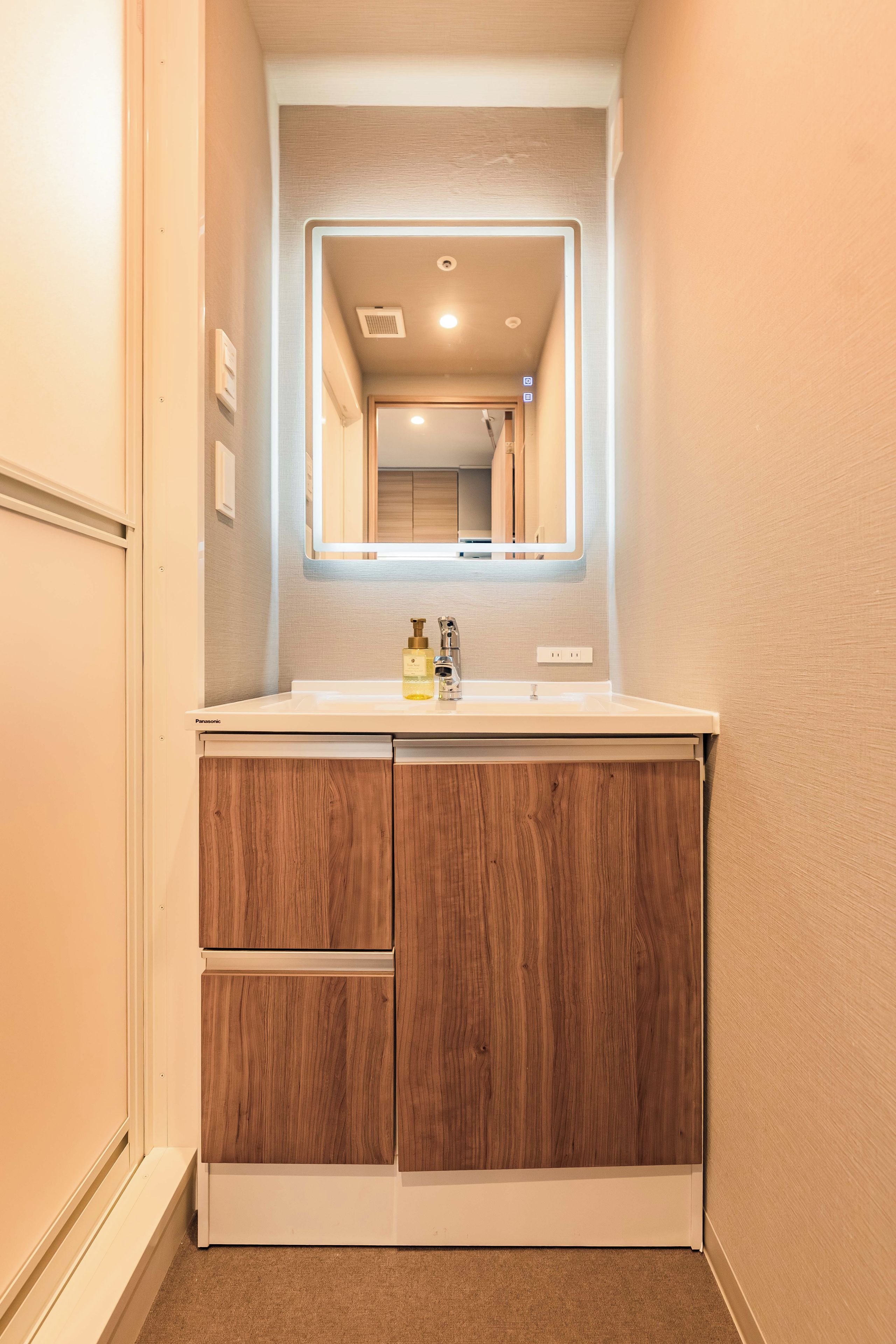 Een badkamer met een wit wastafelmeubel, houten kastjes en een spiegel boven de wastafel.