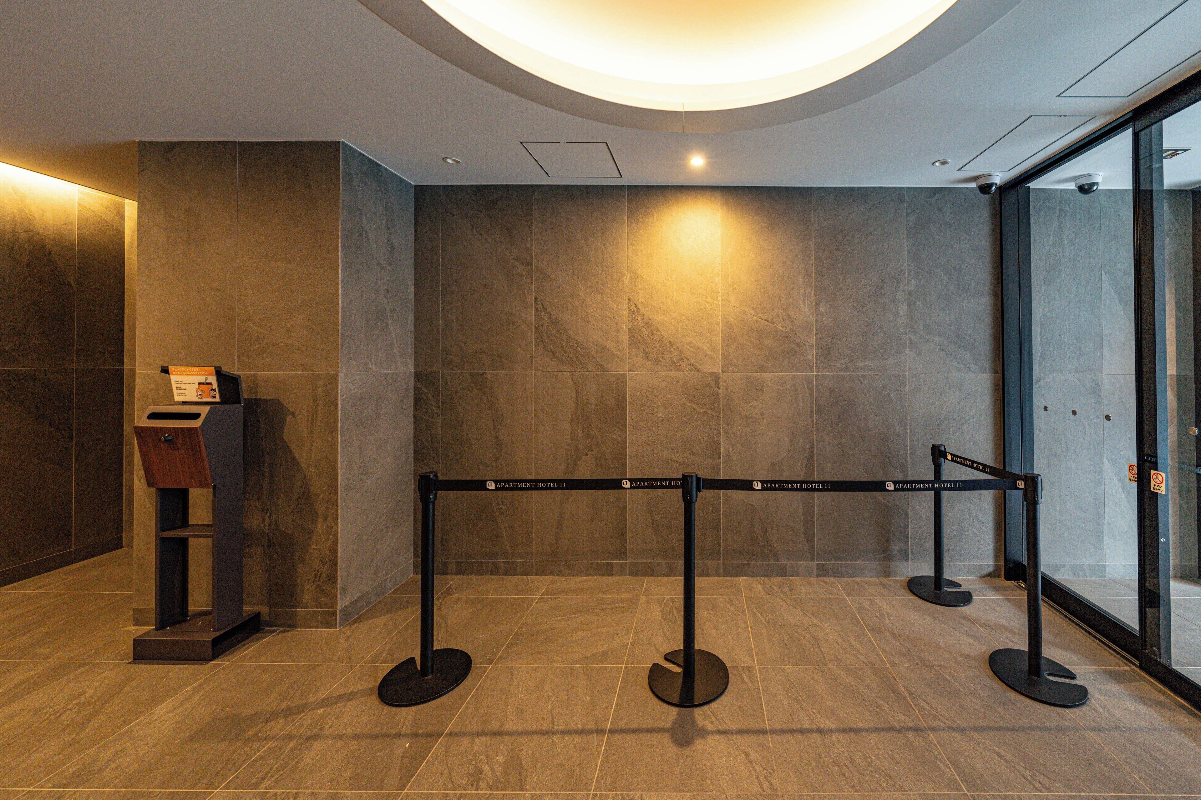Eine moderne Hotelhalle mit Empfangstresen, Glastür und Sicherheitsbarriere.