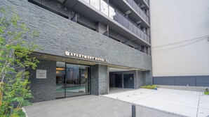 The exterior of Apartment Hotel II with a modern design, featuring a stone facade and a flat entrance area. - Apartment Hotel 11 Namba Minami IV (Osaka)