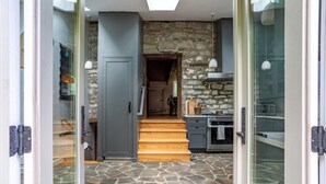 Una cocina moderna con paredes de piedra, una escalera de madera y vista al comedor.