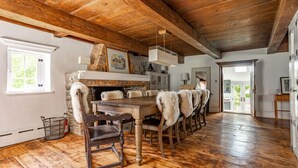 Un comedor rústico con mesa y sillas de madera, una chimenea de piedra y vistas al exterior.