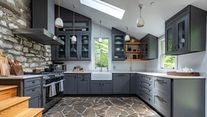 Una cocina moderna con armarios grises, suelo de piedra y tragaluz.