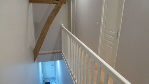 Un escalier à ossature en bois, avec une rampe blanche et une porte sur le côté droit.