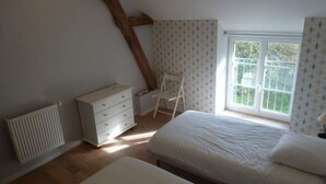 Une chambre à coucher comprenant un lit, une commode, une chaise, un radiateur et une fenêtre donnant sur un paysage agréable.