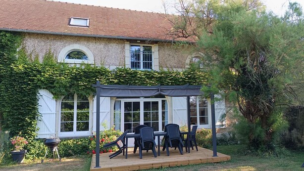 Une maison dotée d’un patio couvert, d’un barbecue et d’un jardin.