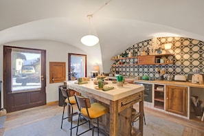 A kitchen with a large island, wooden cabinets, and a patterned backsplash. - La Baita 1800 Ski In Ski Out (Claviere)