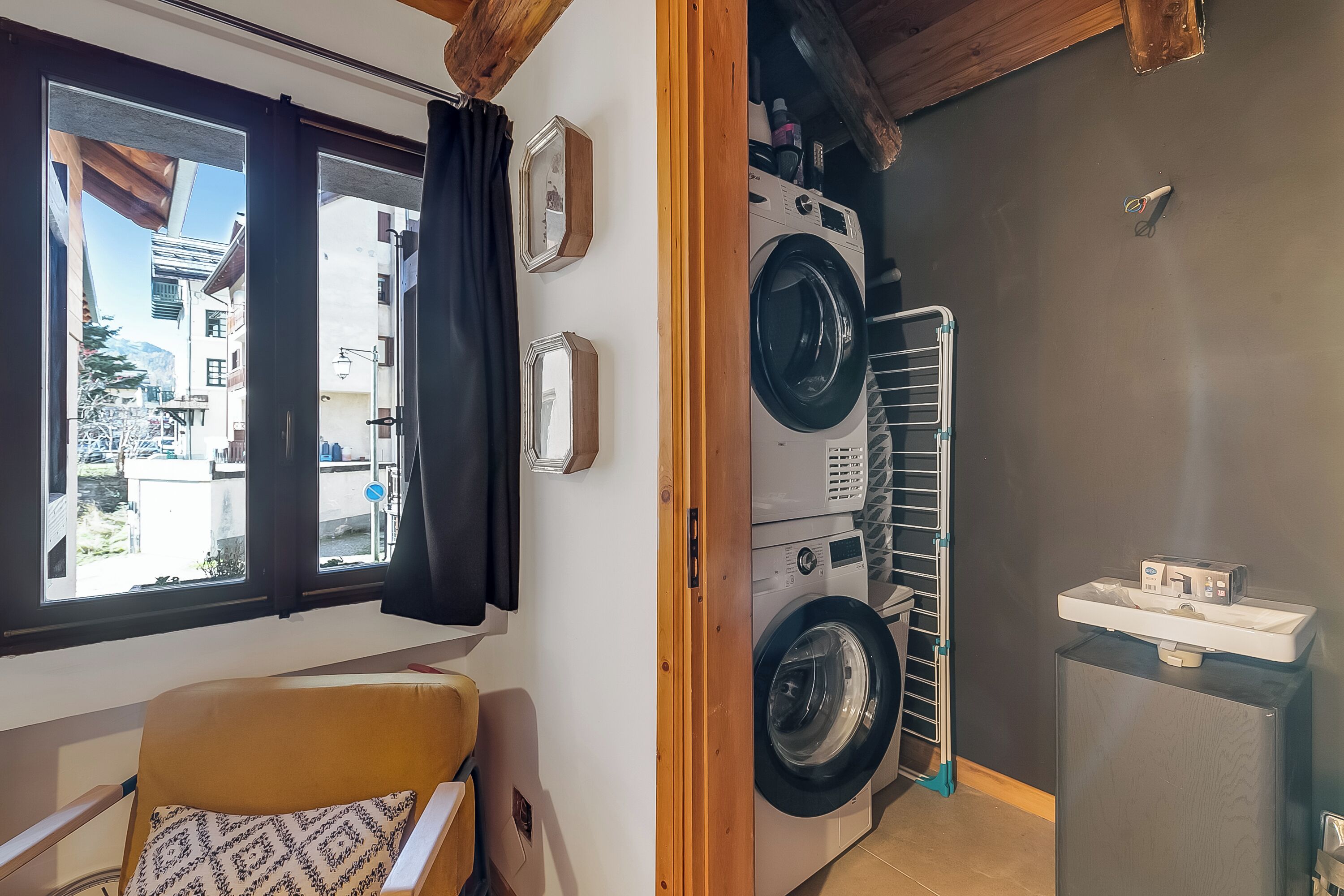 Un espace buanderie comprenant un lave-linge, un étendoir et un petit réfrigérateur.