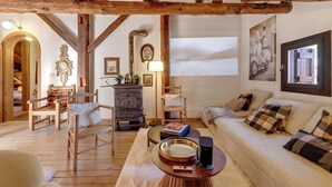 A cozy living room with wooden beams, a sofa, chairs, a coffee table, and a fireplace. - La Baita 1800 Ski In Ski Out (Claviere)