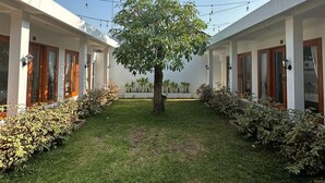 En innergård med ett stort träd i mitten, omgiven av tvåvåningsbyggnader med balkonger och ljusslingor som hänger uppe.