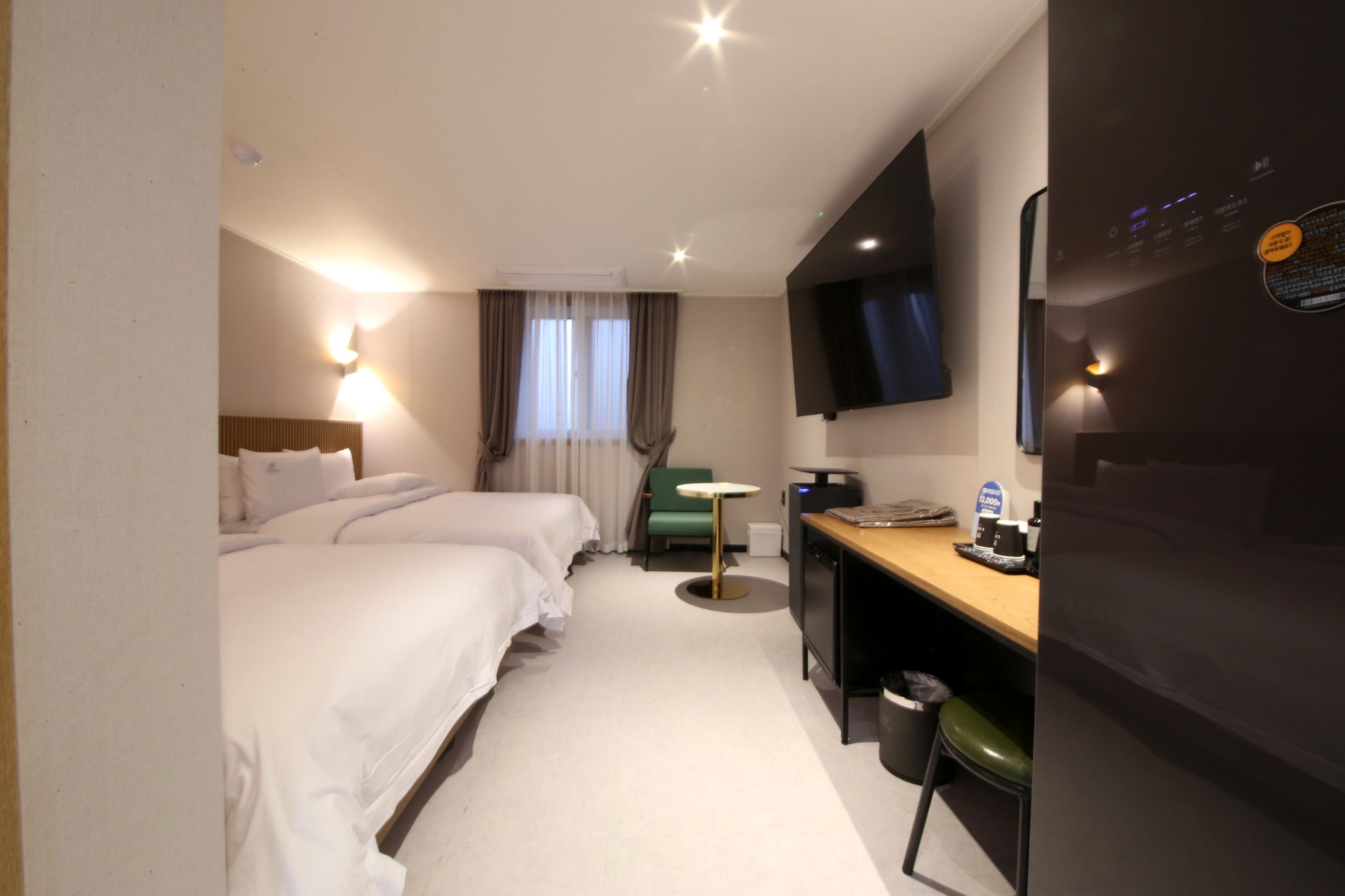 A hotel room with two beds, a desk, a chair, a television, and a small table.