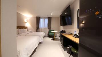 A hotel room with two beds, a desk, a chair, a television, and a small table.