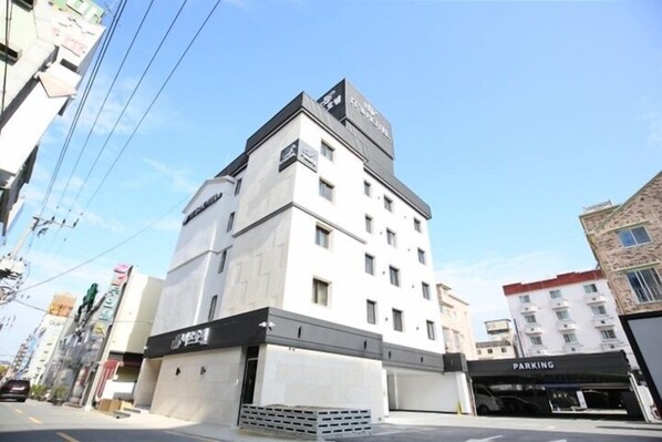 A multi-story hotel with a parking garage and a sign indicating a parking area. - Its HOTEL (Jeonju)