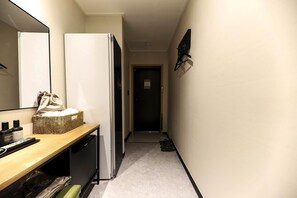 A narrow hallway with a wooden bench, a refrigerator, a basket with toiletries, and a mirror on the left wall. - Its HOTEL (Jeonju)