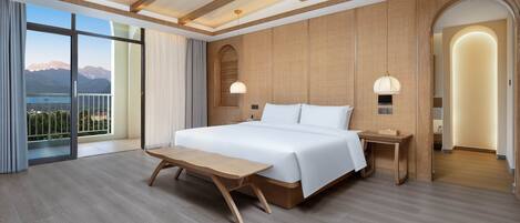 Une chambre d’hôtel moderne dotée d’un grand lit, d’un plancher en bois, de grandes fenêtres offrant une vue sur les montagnes et d’un balcon.